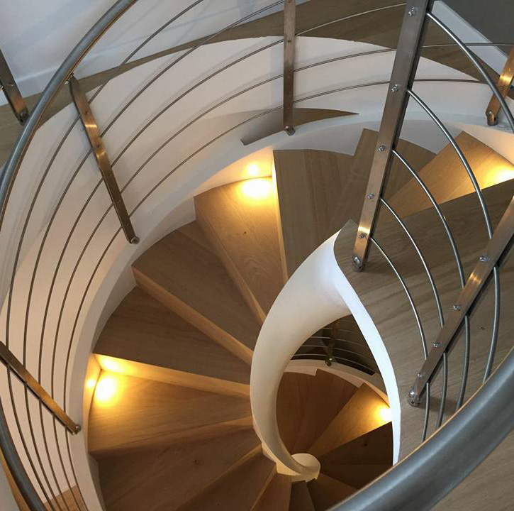 Escalera helicoidal con peldaños de madera y focos realizada en Modena